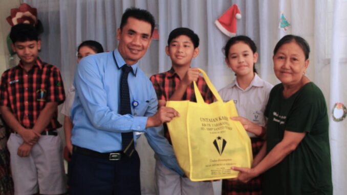 SD Santo Yosef Tarakanita Surabaya melalui kegiatan Aksi Natal berupa pembagian paket sembako kepada warga sekitar